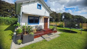 Ein zweigeschossiges Haus mit Balkon, kleiner Veranda und Garten.