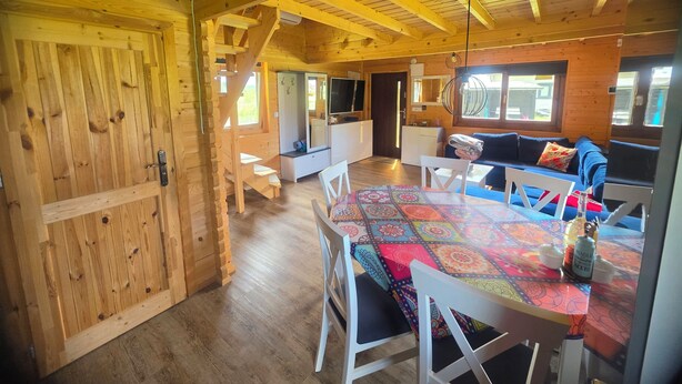 Ein Holzblockhaus-Interieur mit Essbereich, einer Couch und einer Küche.