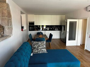 Een moderne keuken met witte kasten, een zwart aanrecht en een roestvrijstalen koelkast.