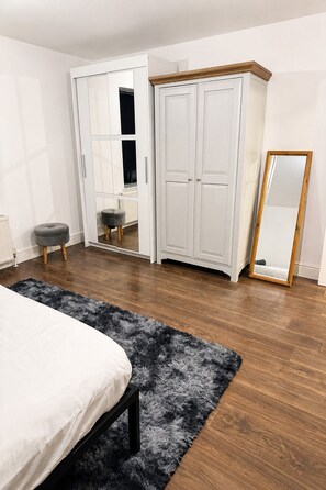 Ein Schlafzimmer mit einem Bett, einem Kleiderschrank, einem Spiegel und einem Teppich.