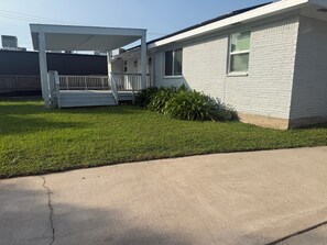 A residential building with a covered porch, a lawn, and a concrete driveway. - 3-bedroom 2-1/2 bath house in beautiful Galveston walk to the beach (Galveston)