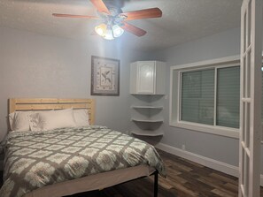 A bedroom with a bed, a ceiling fan, a window, and a wall-mounted cabinet. - 3-bedroom 2-1/2 bath house in beautiful Galveston walk to the beach (Galveston)