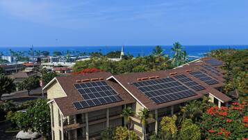 A building with multiple floors, solar panels on the roof, and a view of the ocean.