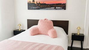 Een slaapkamer met een bed, twee nachtkastjes, een ventilator in het plafond en een schilderij van de Eiffeltoren.