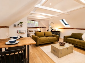 Ein gemütlicher Loft-Wohnraum mit Essbereich, zwei Sofas, einem Holztisch und einem Oberlicht.