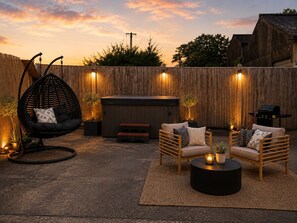 Eine Außenpatio mit Whirlpool, Sitzgelegenheit und Grill.