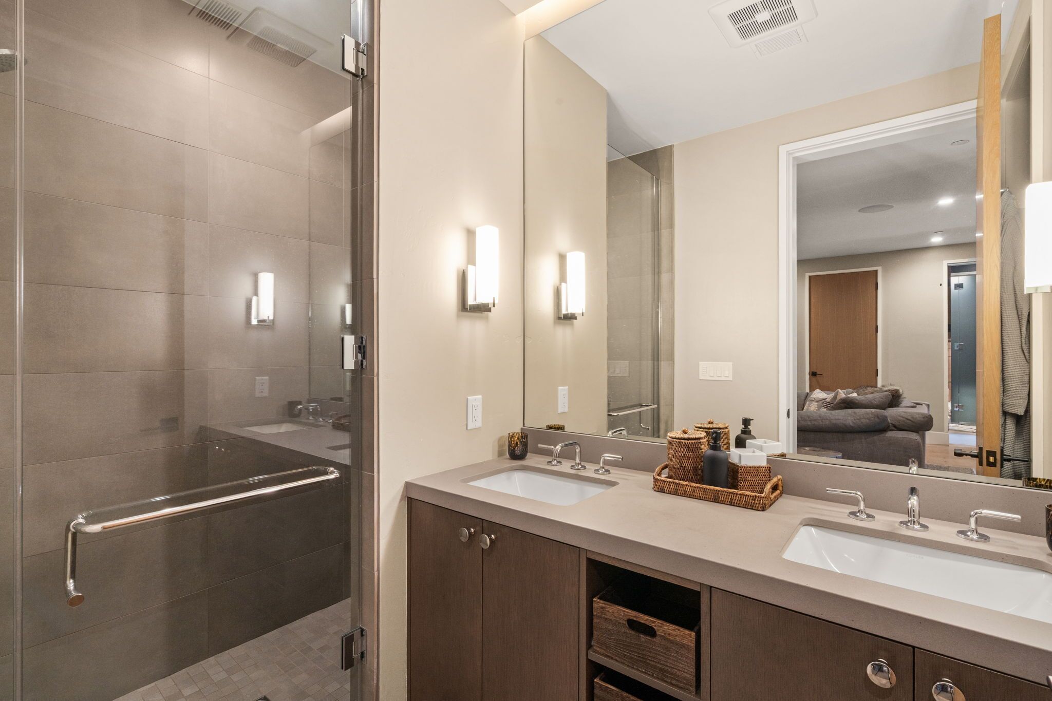 A modern bathroom with a glass shower enclosure, two sinks, and a large mirror.