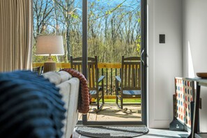 Een kamer met een bed, een lamp en uitzicht op een terras met stoelen en een tafel.