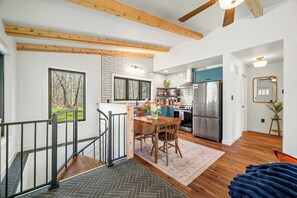 A modern kitchen with a stainless steel refrigerator, a microwave, and a stove. There is a dining area with a table and chairs. - Cozy 2-bedroom cottage in serene Brown County Indiana (Nashville)