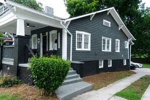 Ein zweistöckiges Haus mit Veranda, kleinem Vorgarten und Auffahrt.