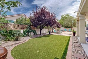 A backyard with a lawn, a tree, a patio area with chairs, and a fence. - The Vibrant Haven! Close to Golfing, Park, Sights (Albuquerque)