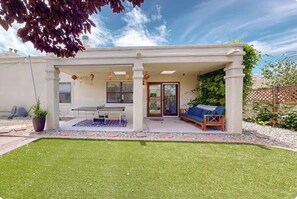 A covered patio with a ping pong table, a sofa, and a small garden area. - The Vibrant Haven! Close to Golfing, Park, Sights (Albuquerque)