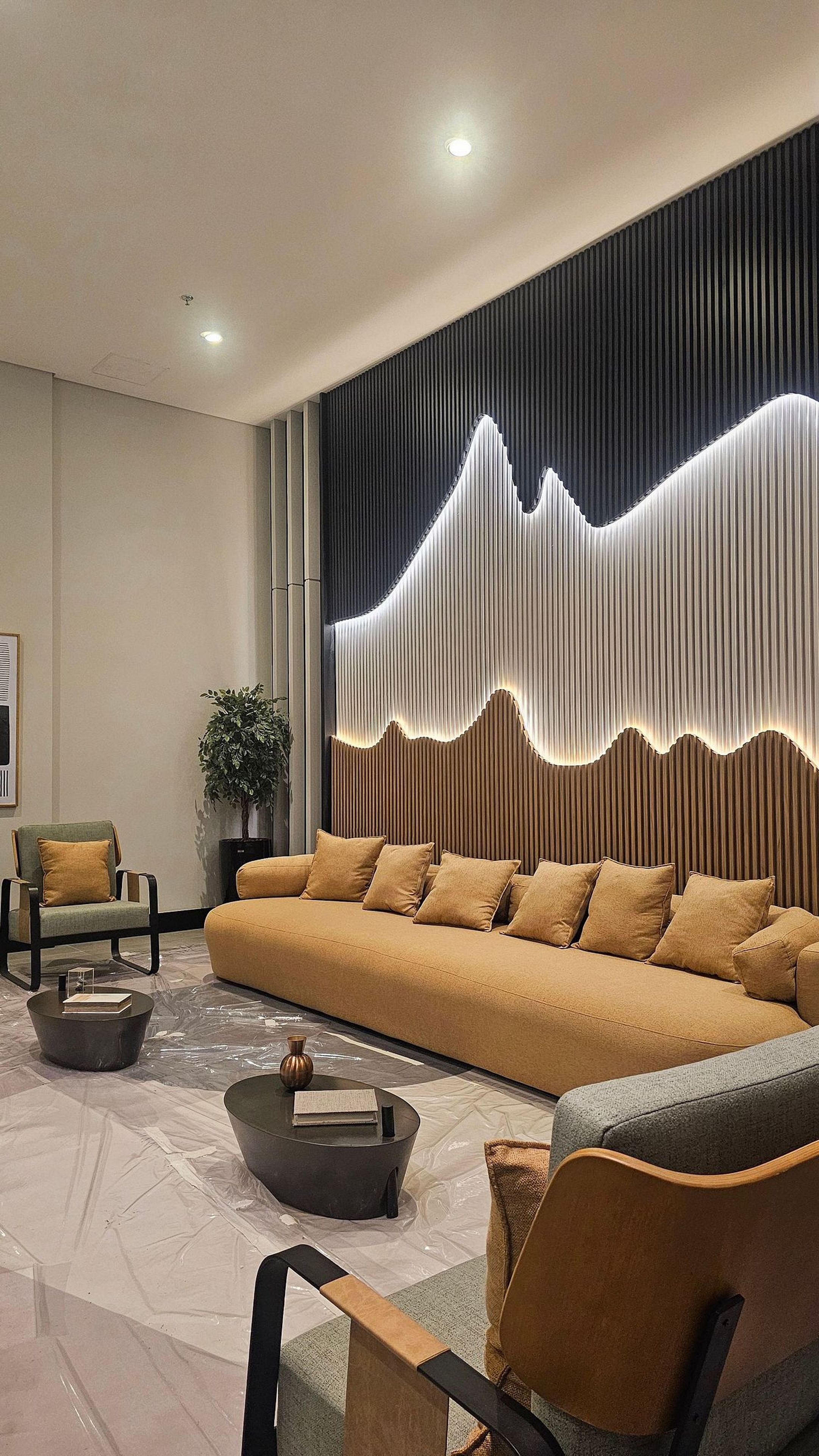 Una sala de estar moderna con sofá, sillas y un panel decorativo en la pared.