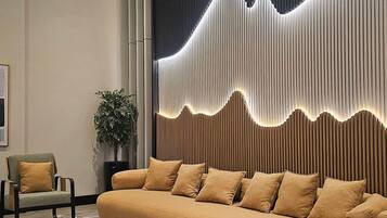 Una sala de estar moderna con sofá, sillas y un panel decorativo en la pared.