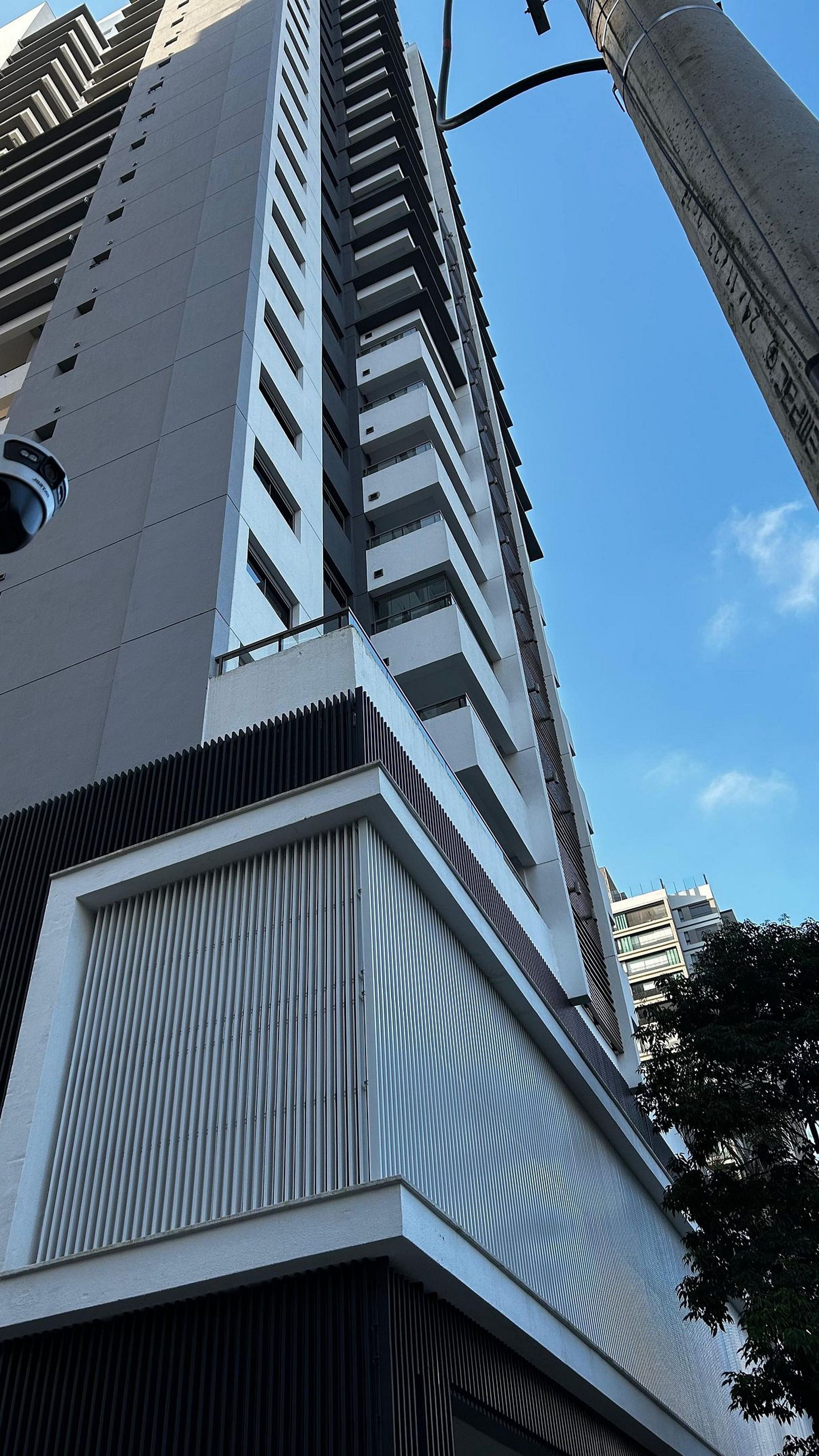 A high-rise building with a modern architectural design, featuring a prominent vertical structure and a series of balconies.