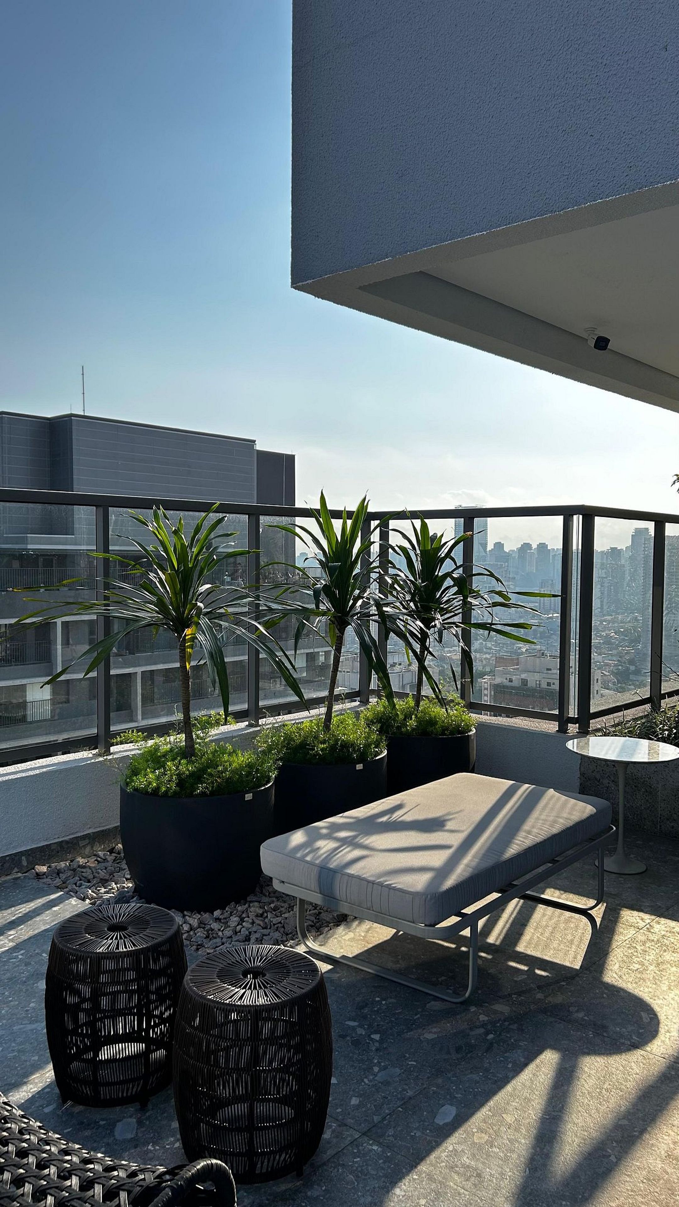 A rooftop terrace with a seating area, potted plants, and a view of the cityscape.