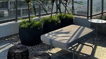 A rooftop terrace with a seating area, potted plants, and a view of the cityscape.