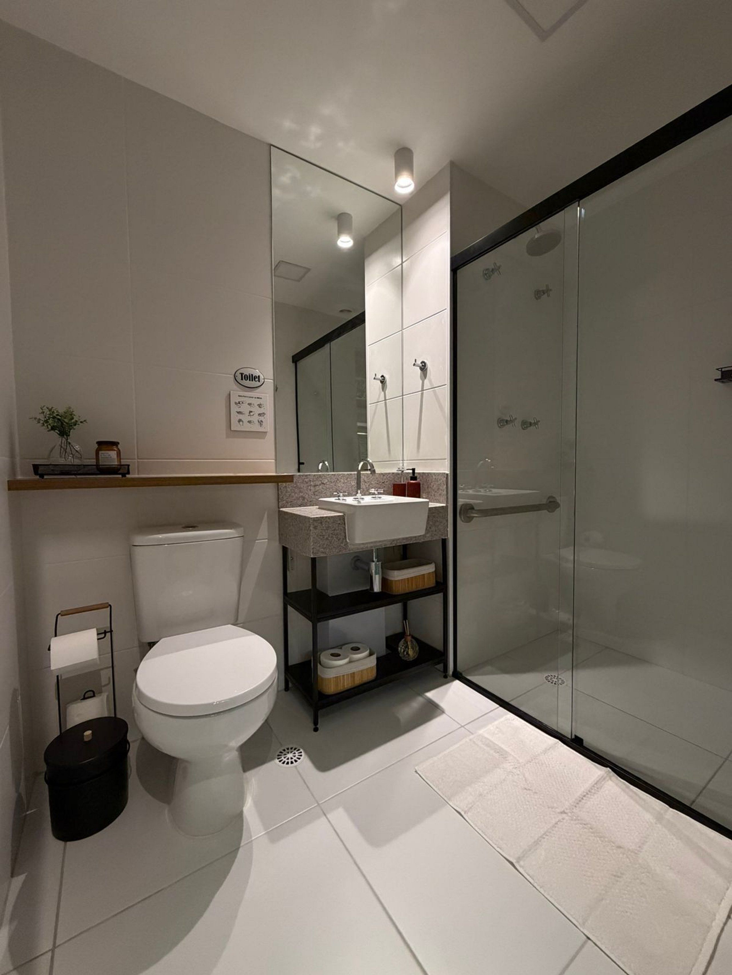 Un baño moderno con inodoro, lavamanos y cabina de ducha de vidrio.