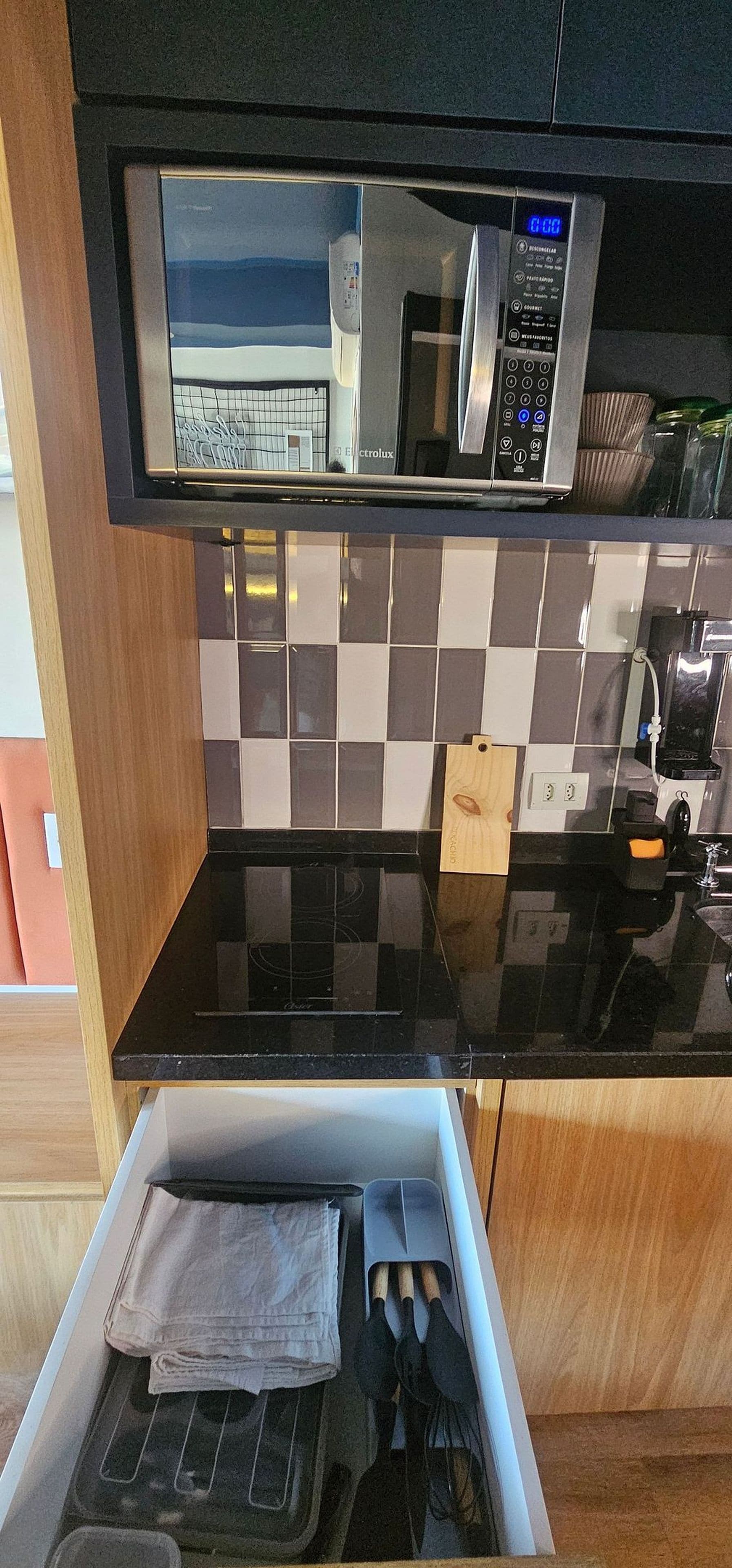 Eine Küche mit Mikrowelle, Kaffeemaschine und einer Schublade voller Küchenutensilien.