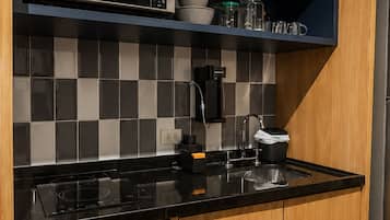 A modern kitchen with a microwave, coffee maker, and a sink.