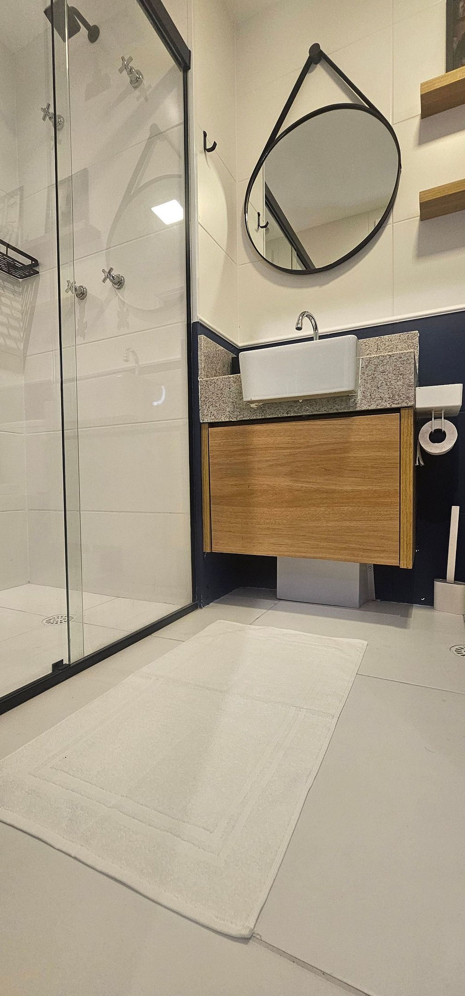 Un baño con cabina de ducha de vidrio, un lavabo con tocador de madera y un espejo en la pared.