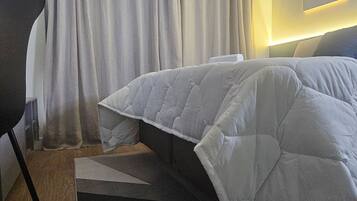 A hotel room with a bed, a chair, a rug, and a wall-mounted light fixture.