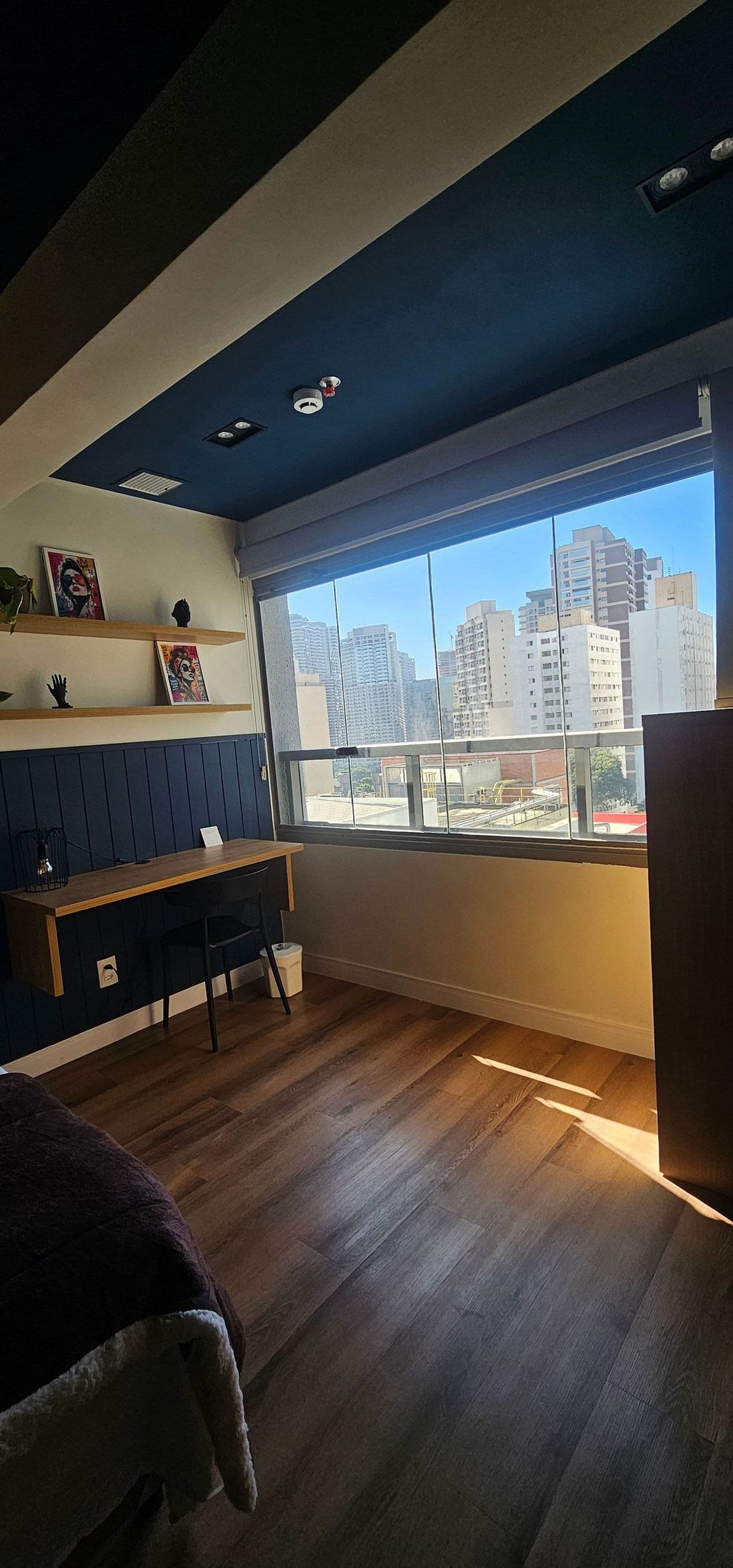 A room with a large window, a desk, and a chair.