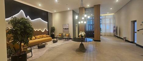 A spacious lobby with a sofa, chairs, a coffee table, and a large plant.