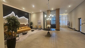 Un hall d’entrée spacieux, aménagé avec un canapé, des fauteuils, une table basse et une grande plante.