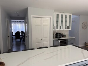 A modern kitchen with white cabinets, a marble countertop, and a dining area with a table and chairs.