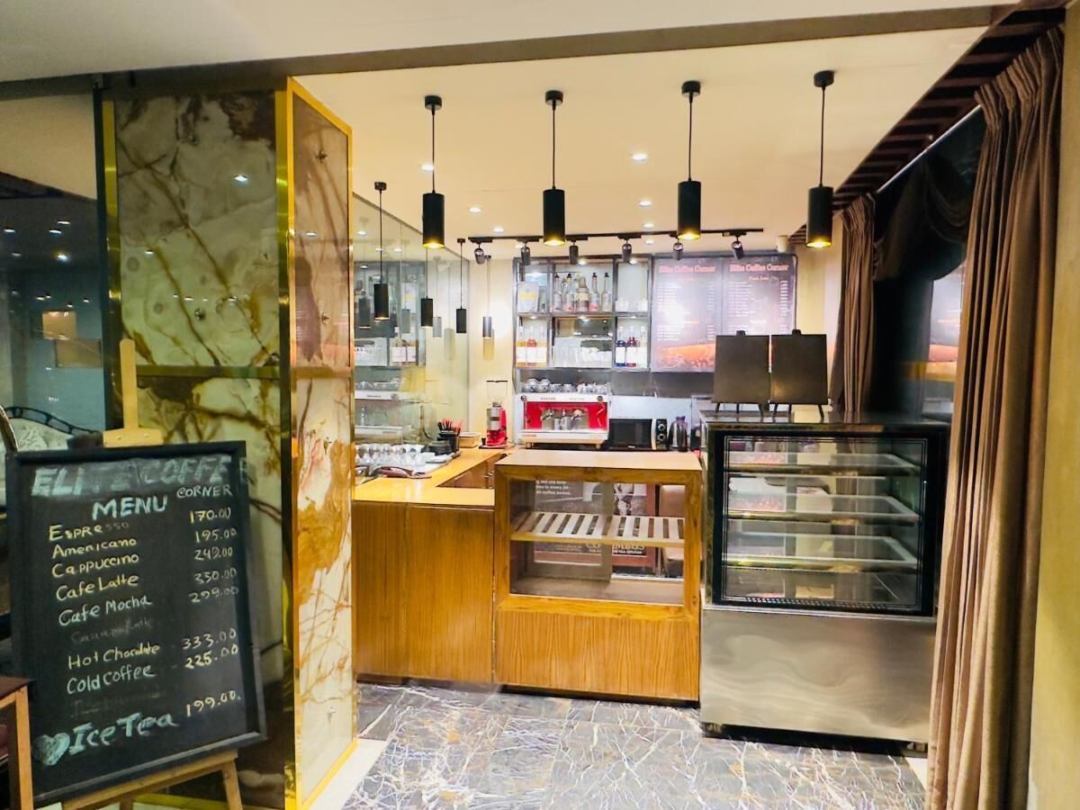 L’intérieur d’un café, avec un tableau affichant le menu, une machine à expresso et une vitrine.