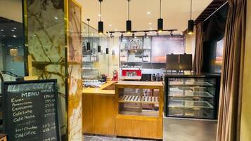 L’intérieur d’un café, avec un tableau affichant le menu, une machine à expresso et une vitrine.