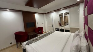 Ein Hotelzimmer mit einem Bett, einem Schreibtisch, zwei Stühlen, einem Fernseher und einem Spiegel.