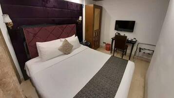 Una habitación de hotel con una cama grande, televisión, escritorio y una silla.