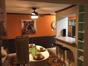 A dining area with a round table, chairs, and a painting on the wall. - Spacious 2BR Condo 208 (Dallas)