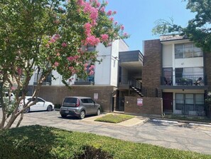 A two-story building with a parking area in front. - Spacious 2BR Condo 208 (Dallas)