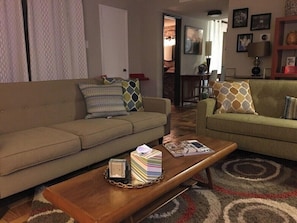 A living room with a sofa, a coffee table with books and a lamp, and a patterned rug. - Spacious 2BR Condo 208 (Dallas)