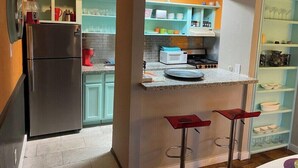 Eine Küche mit Kühlschrank, Mikrowelle und Barhocker.