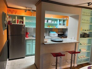 A kitchen with a refrigerator, microwave, and bar stools. - Spacious 2BR Condo 208 (Dallas)