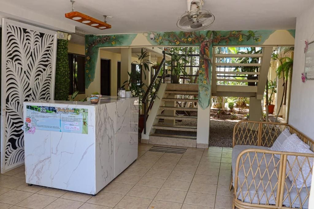 A reception area with a marble counter, a staircase leading to a covered outdoor area, and a wicker sofa.