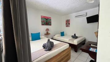 Habitación de hotel con dos camas, un escritorio, una silla, una lámpara y obras de arte en las paredes.