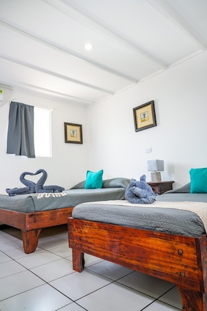 Una habitación con dos camas de madera, una ventana con cortinas y dos cuadros en la pared.