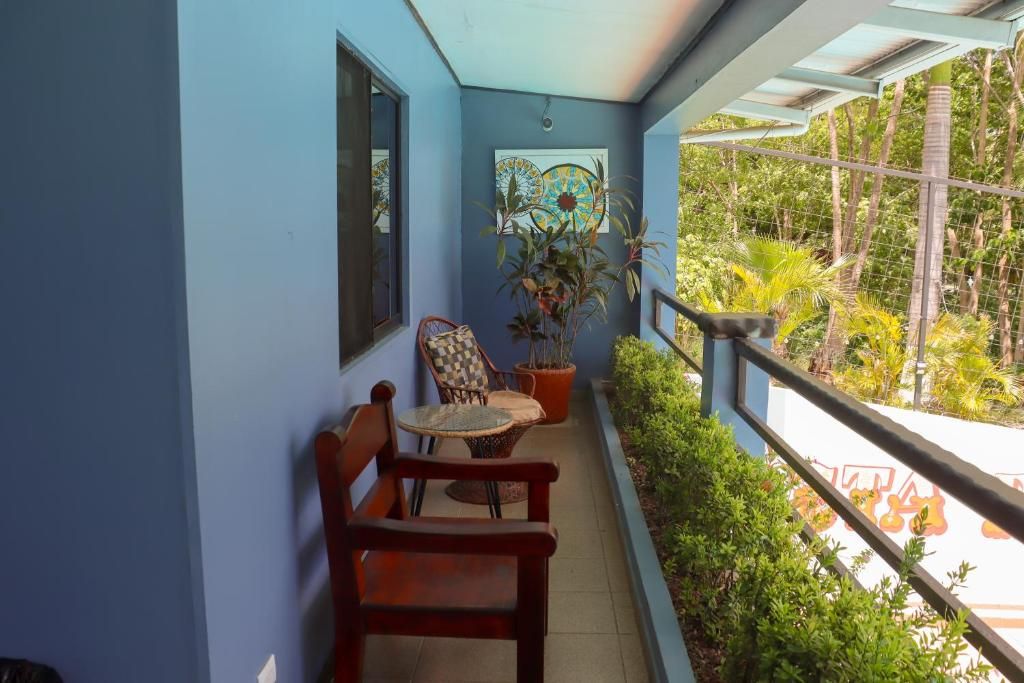 Un balcon avec un mur bleu, une chaise en bois, une petite table et une plante en pot.