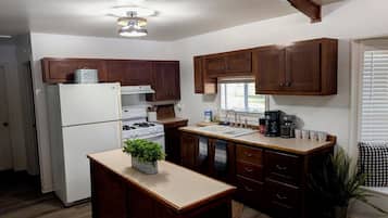 Une cuisine de taille réduite, avec des meubles en bois, un réfrigérateur blanc, une cuisinière et un évier.
