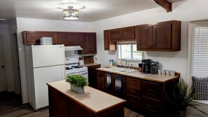 A compact kitchen with wooden cabinets, a white refrigerator, a stove, and a sink.