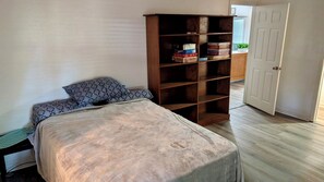 A bedroom with a bed, a wooden bookshelf, and a door.