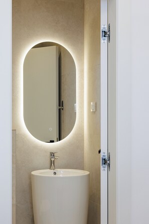 A bathroom with a large oval mirror, a sink, and a door with a handle.
