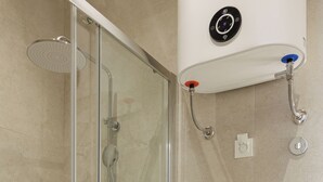 Un bagno moderno con doccia vetro, un water e un portasciugamani.