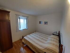 A bedroom with a single bed, a window, a wooden wardrobe, and two small wall decorations. - Peaceful Two Bedroom Stone House in the Heart of Vis Island  (Podhumlje)