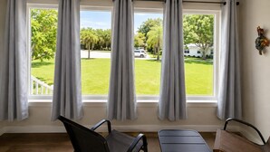 Een kamer met een groot raam, een bank en een stoel.